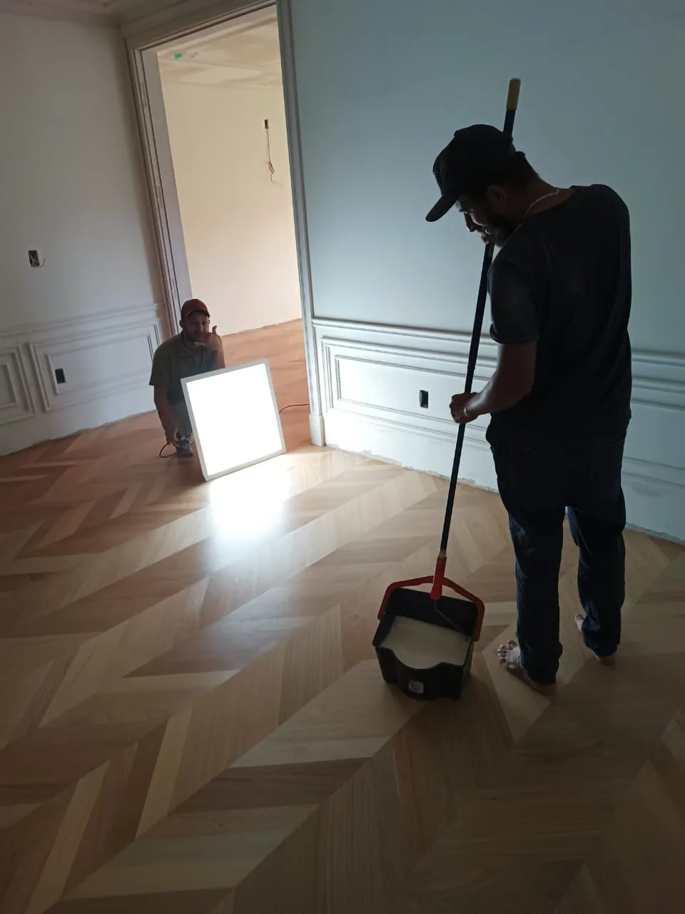 Equipe Renova Tacos conferindo acabamento de piso de madeira com luz técnica